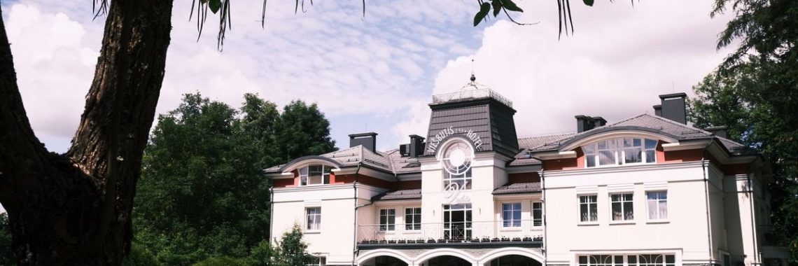 Elegant architecture of Druskininkai's Grand Spa Hotel surrounded by lush greenery.