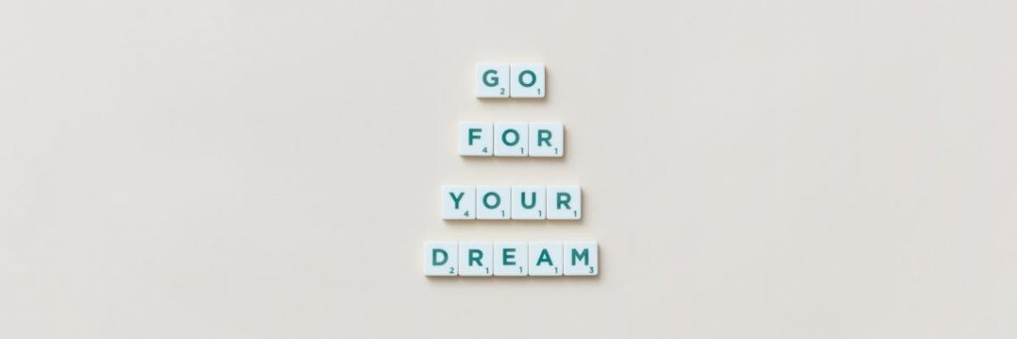 Inspirational text 'Go For Your Dream' made from Scrabble tiles on a plain background.