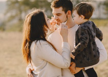 Family sharing affectionate moments outdoors with parents and child enjoying the sunny day.