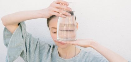 An artistic portrait featuring a person holding clear glass with water, creating a unique visual effect.