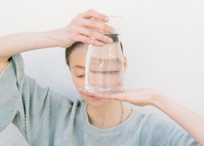 An artistic portrait featuring a person holding clear glass with water, creating a unique visual effect.